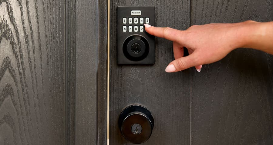 Finger pushing the keypad of a Vivint smart lock from Kwikset
